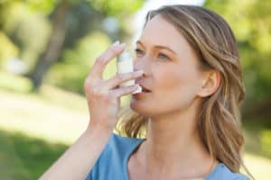 Frau mit Asthma-Inhalator im Park